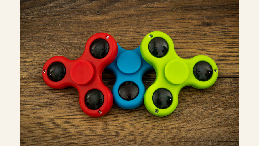 Three red, blue and green fidget spinners arranged together.