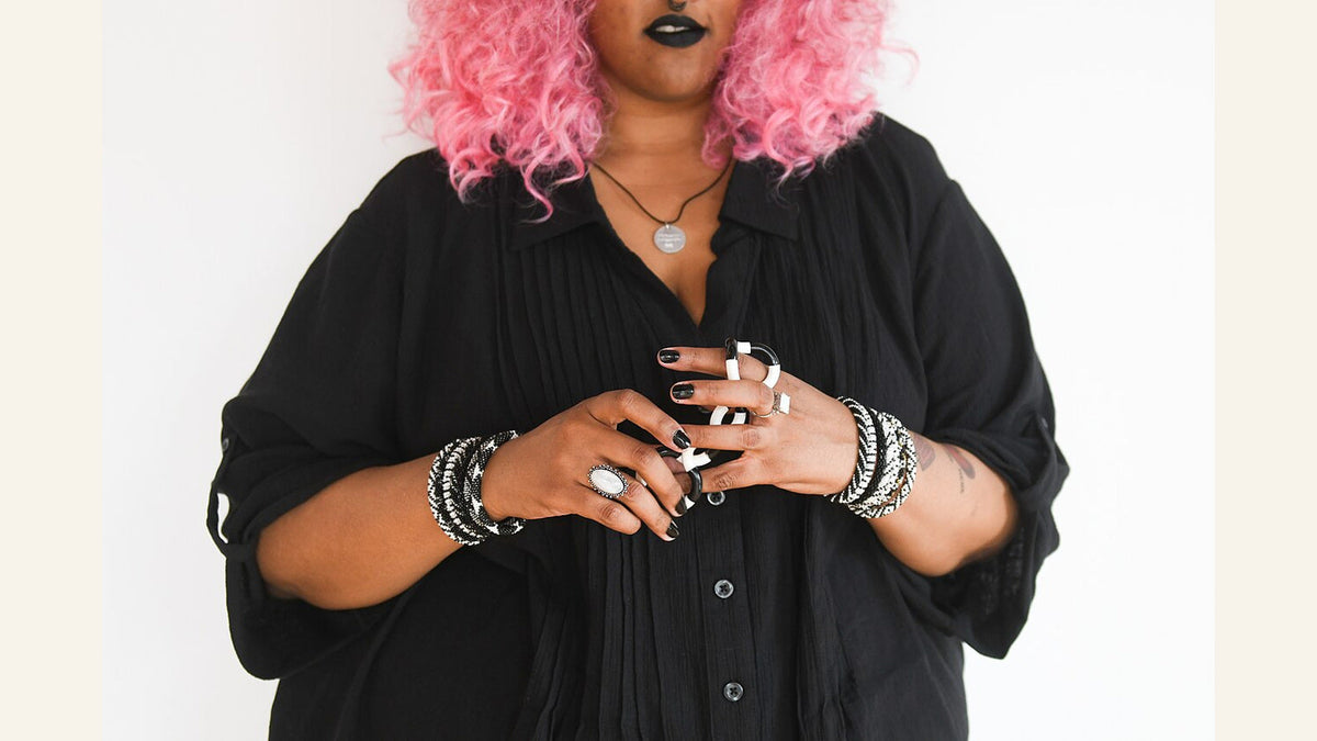 Pink-haired person in a black shirt holding a black-and-white Tangle toy.
