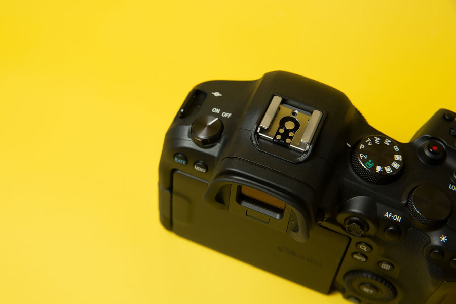 Close-up of a black camera with a textured grip against a yellow background.