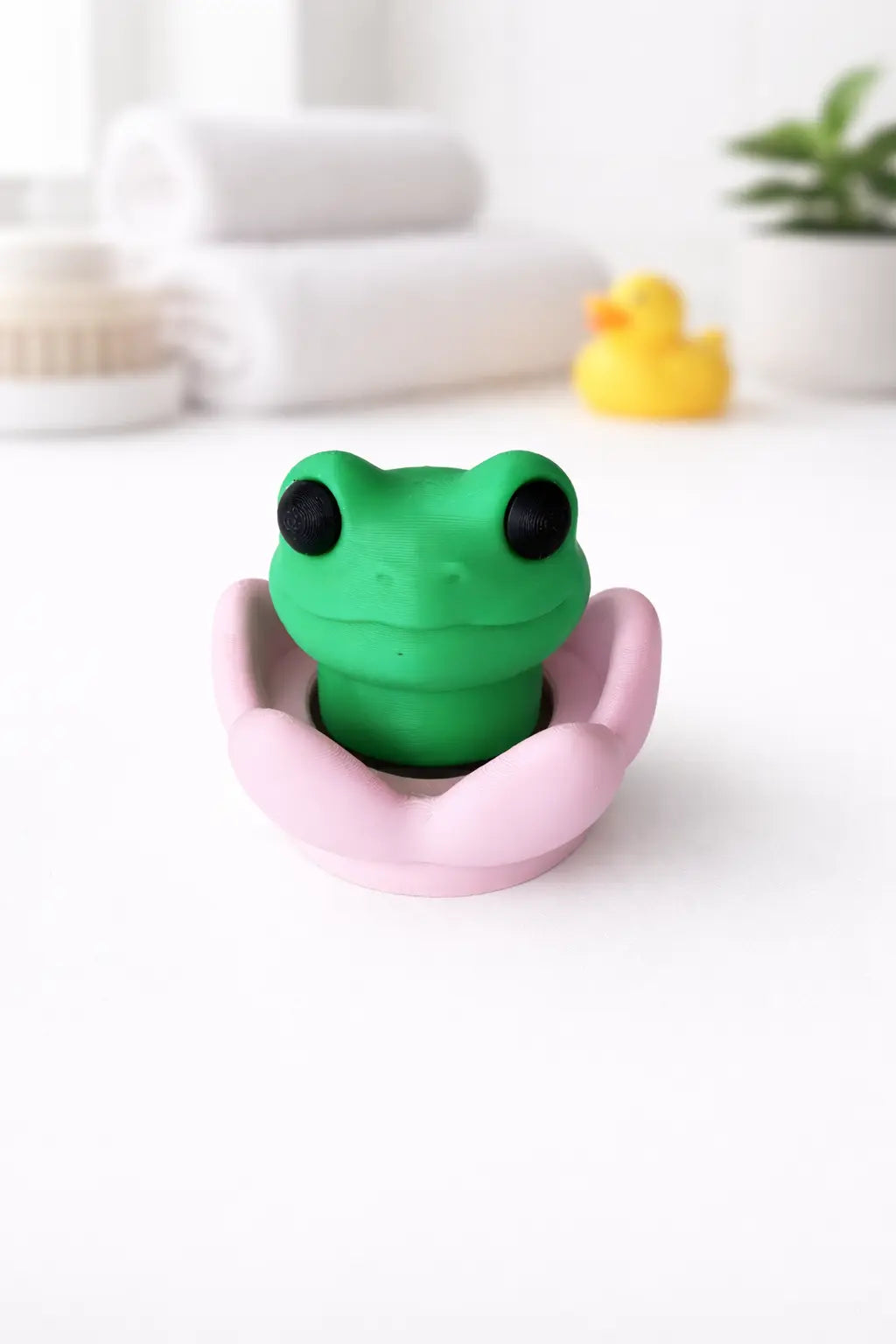 Green frog clicker resting in a pink lily-pad base