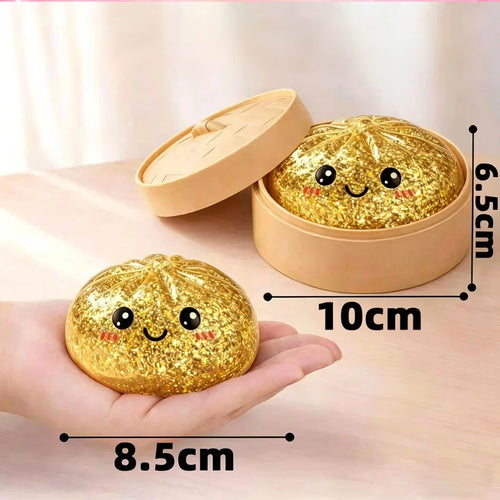 Hand holding a gold glitter dumpling squishy beside a tan steamer-style container