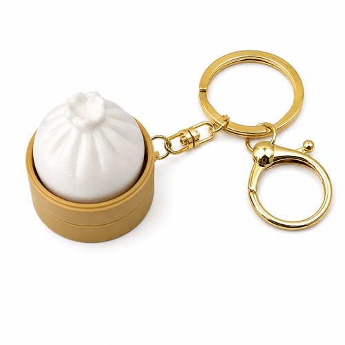 White dumpling-shaped clicker in a tan steamer base with a gold-tone key ring and clasp